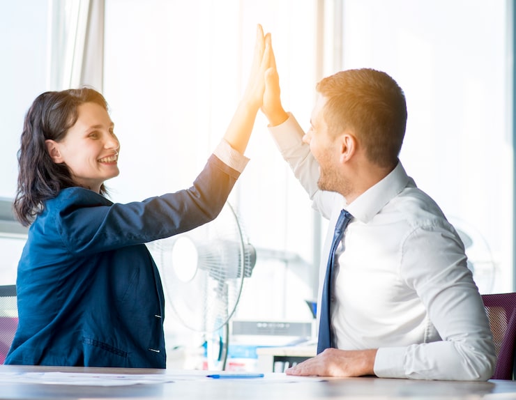 High five between two smiling professionals in an office, representing excellent customer service and insurance solutions at Nick Godfrey Insurance Inc.